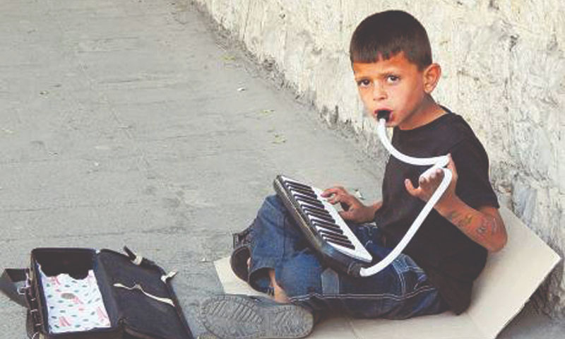 طفل بلا مأوى يعزف الموسيقى في الشوارع بالقرب من جامعة دمشق. (gulfnews)
