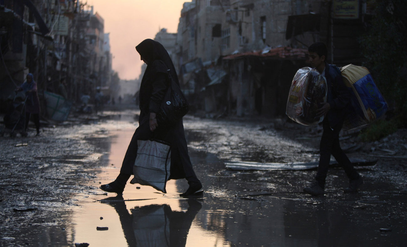 امرأة تعبر طريقًا مهجورًا في مدينة الحجيرة  جنوب دمشق (رويترز)