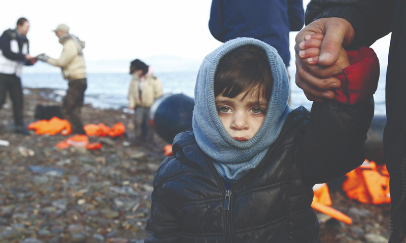 طفل سوري لاجئ مع أبيه على الشواطئ اليونانية -(رويترز / جيورجوس موتيفيس)