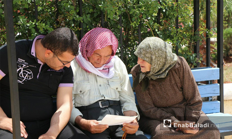 سكان من مدينة عفرين يقرأون بروشورات حملة نحنا أهل الموزعة من فصيل أحرار الشرقية - 16 من أيار 2018 (عنب بلدي)
