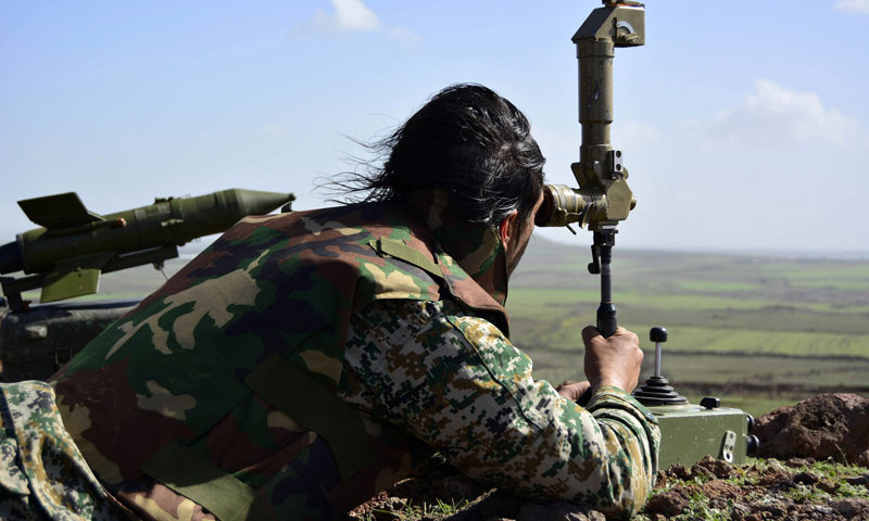 مقاتل من قوات الأسد يحدد وجهة صاروخ مضاد للدروع في تل فاطمة المطل على بلدة كفرسمس شمال درعا - آذار 2015 (AFP)