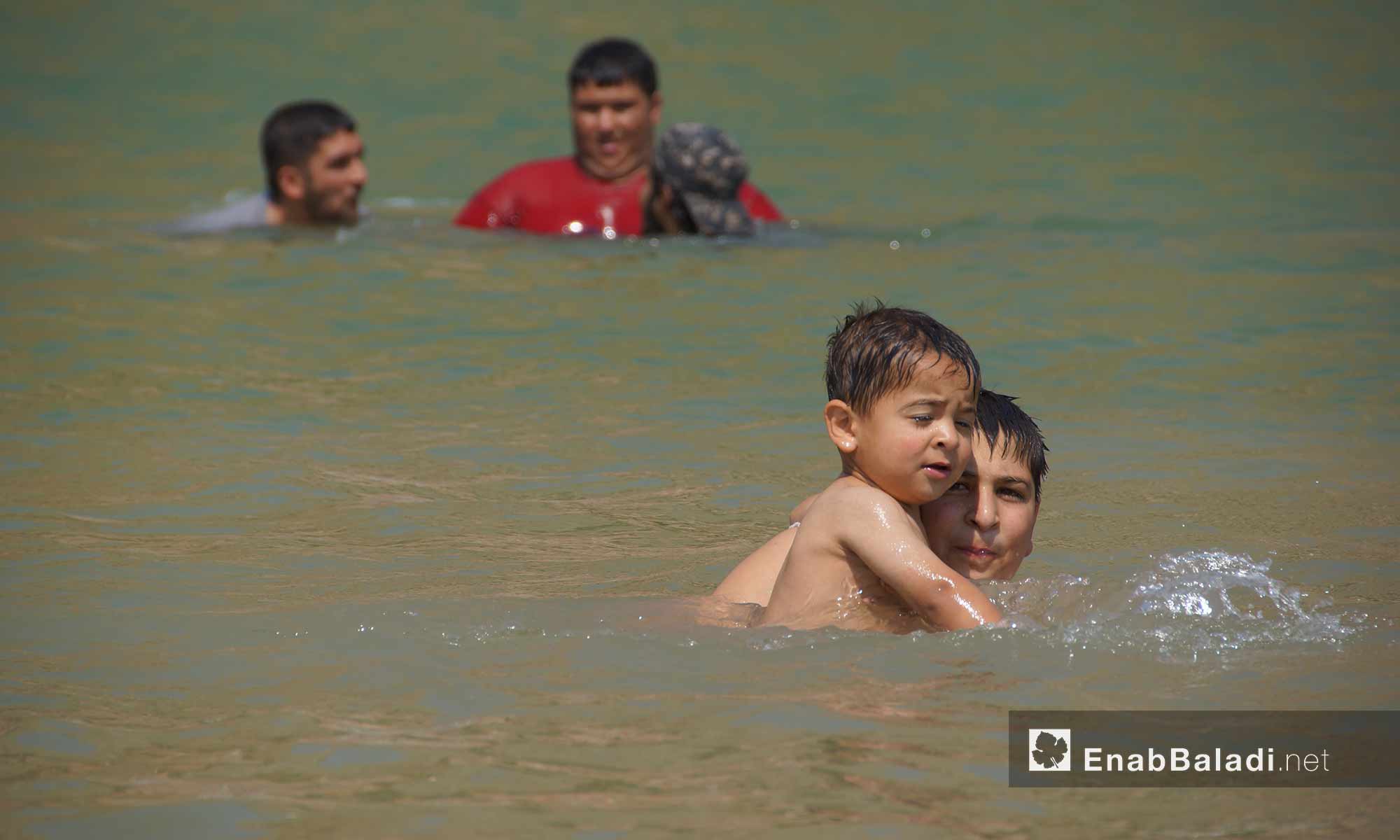 أطفال وعائلات يسبحون في بحيرة نبع قرية "باب الطاقة"  غربي حماة - 13 تموز 2018 (عنب بلدي)
