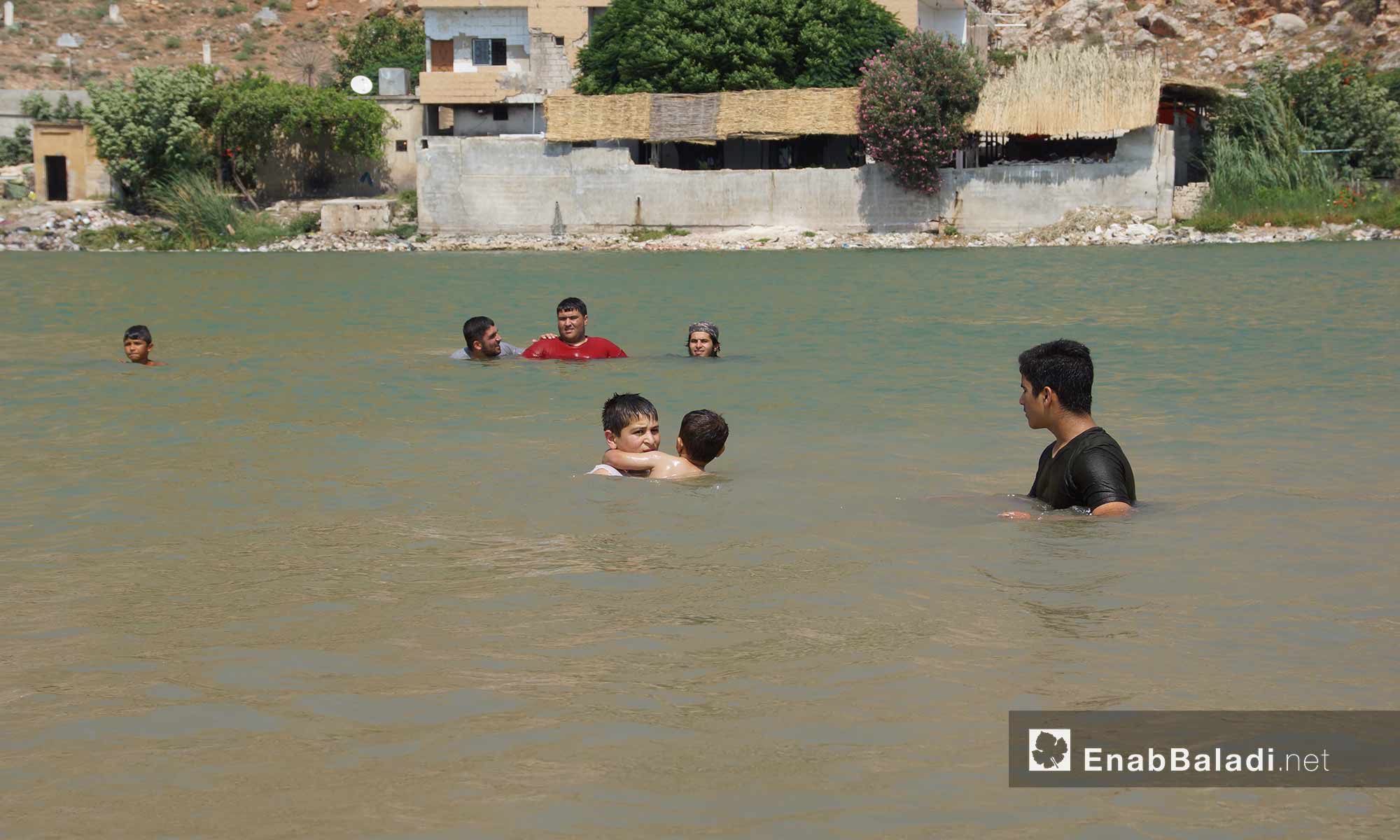 أطفال وعائلات يسبحون في بحيرة نبع قرية "باب الطاقة"  غربي حماة - 13 تموز 2018 (عنب بلدي)