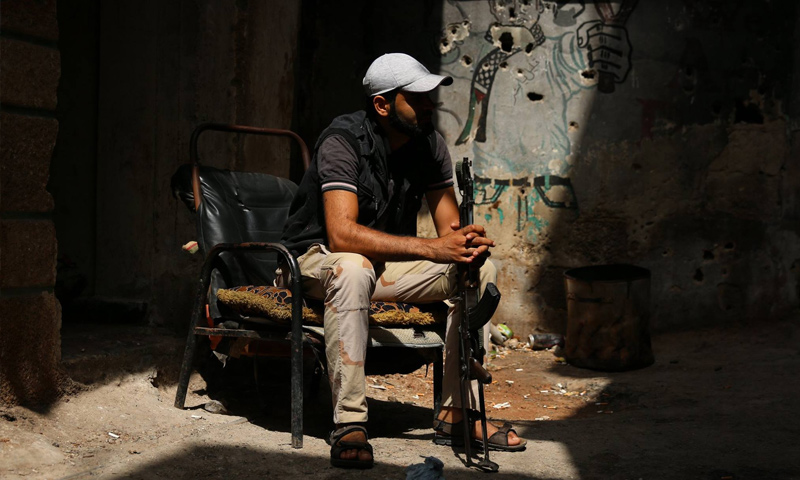 مقاتل الجيش السوري الحر يجلس مع سلاحه في منزله - 13 تموز 2017 (علاء الفقير/ رويترز)