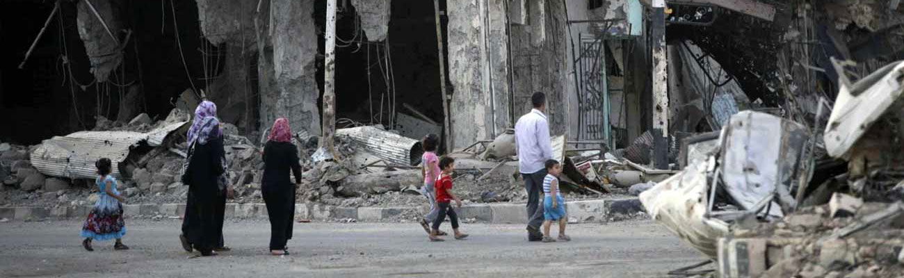 سوروين يمشون ضمن الدمار في دير الزور (رويترز)
