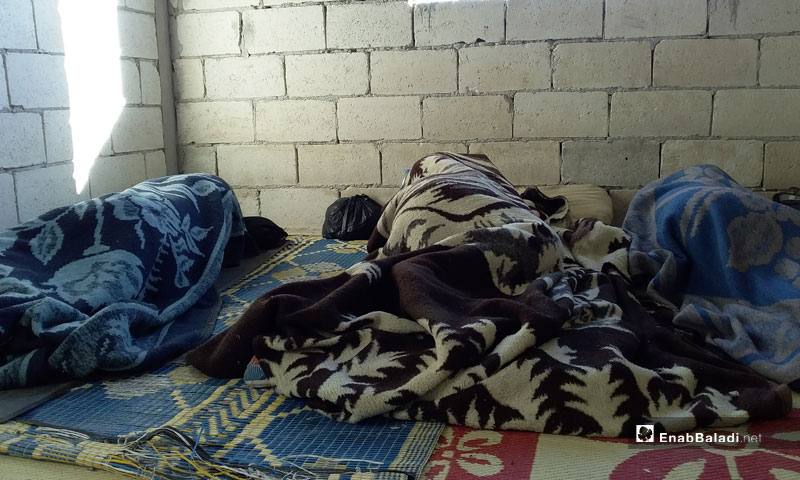 شباب عرب نائمون في بلدة هتيه بريف إدلب في أثناء محاولتهم العودة إلى تركيا- تموز 2018 (عنب بلدي)

