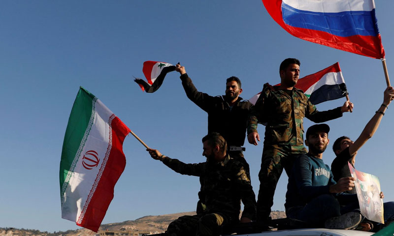 مقاتلون يرفعون علم روسيا وإيران تنديدًا بالاعتداءات الأمريكية على سوريا -نيسان 2018 (رويترز)
