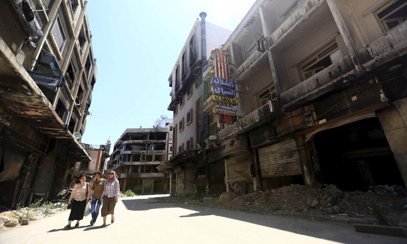 سيدات يمشين في حي مدمر في حمص القديمة - 3 حزيران 2015 (رويترز)
