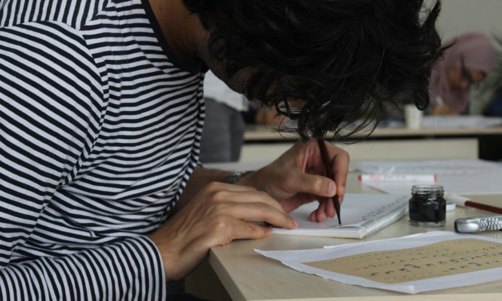 طالب يتدرب على الخط العربي في اسطنبول التركية - 27 حزيران 2018 (صالون مرحبا الثقافي)
