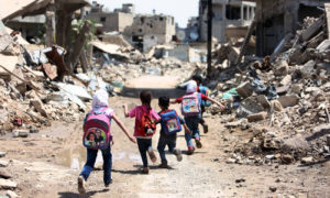 طلاب مدرسة يركضون عبر شارع إلى مدرستهم في الغوطة الشرقية- أيار 2016 (AFP)

