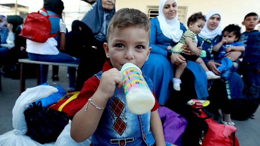 طفل يتناول الحليب قبل عبوره إلى سوريا من لبنان - 17 أيلول 2018 (AFP)