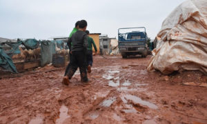 أطفال يسيرون وسط الوحل بعد عاصفة ضربت مخيمات الشمال السوري - 2018 (AFP)
