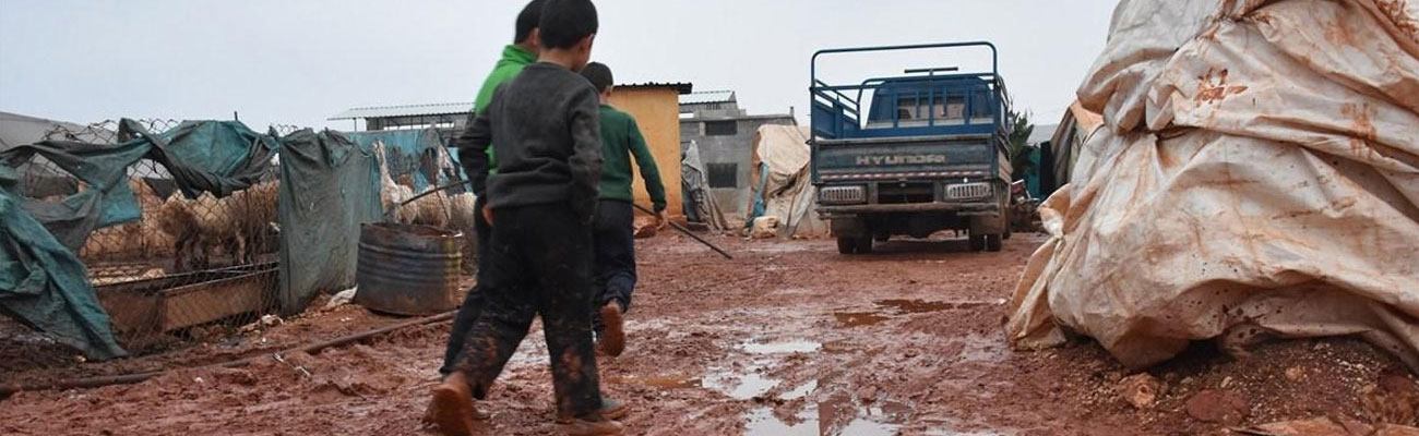 أطفال يسيرون وسط الوحل بعد عاصفة ضربت مخيمات الشمال السوري - 2018 (AFP)
