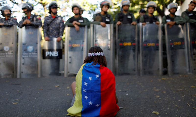 متظاهرة فنزويلية أمام رجال الامن (رويترز)