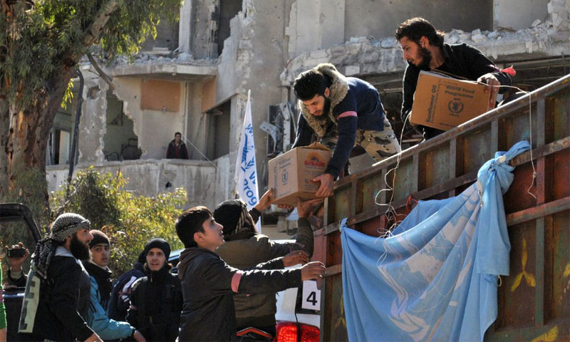 مقاتلون من المعارضة يساعدون بتفريغ مساعدات إنسانية أممية في حمص - شباط 2014 (AFP)