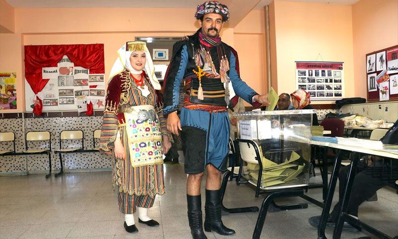 زوجان في ولاية آيدين التركية يتجهان إلى مركز الاقتراع للإدلاء بصوتيهما في الانتخابات المحلية، مرتديين الزي التقليدي الخاص برقصة إيفيه التي تعد من أهم الرقصات الفلكلورية لدى الشعب التركي - 31 آذار 2019 (TRT)