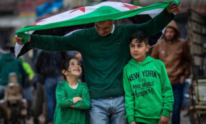 أب يرفع علم الثورة مع أبنائه في مظاهرة بمدينة سرمدا بريف إدلب - 15 آذار 2019 (عمار الزير)