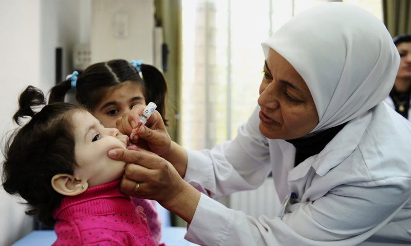 عاملة صحية تقدم لقاح الحصبة لطفلة في دمشق - تشرين الثاني 2013 (AP)