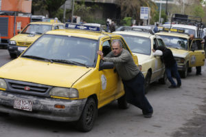 سائقو سيارات الأجرة يدفعون سياراتهم التي نفد منها البنزين إلى محطة محروقات في العاصمة السورية دمشق - 16 نيسان 2019 (AFP)