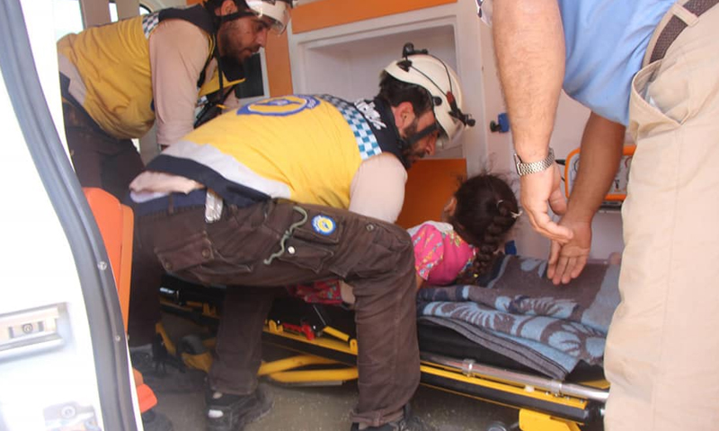 عناصر من "الدفاع المدني" يسعفون طفلة أصيبت جراء القصف في بلدة حاس بريف إدلب (الدفاع المدني)