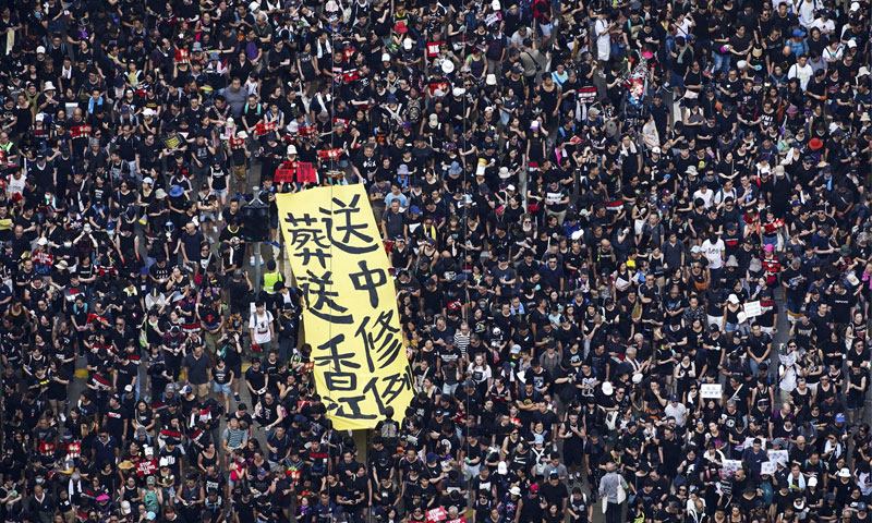 متظاهرين في هونغ كونغ يرفعون راية كتب عليها "قانون تسليم المطلوبين جنازة هونغ كونغ" - 16 حزيران 2019 (AP)