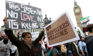 متظاهرون يطالبون الحكومة البريطانية باستقبال المزيد من اللاجئين يحملون لافتة 