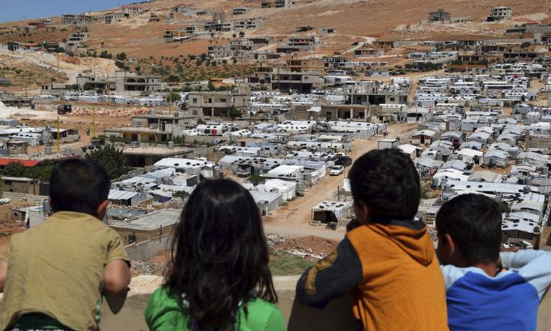 أطفال لبنانيون ينظرون إلى مخيمات السوريين في بلدية عرسال - 19 حزيران 2019 (AP)