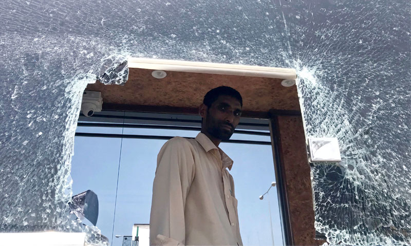 موظف في مطار أبها السعودي ينظر عبر الزجاج المحطم بعد غارة الحوثيين - 24 حزيران 2019 (رويترز)