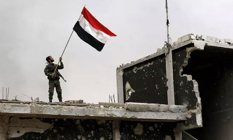 جندي يرفع علم النظام في منطقة الحجر الأسود - 22 أيار 2018 (AFP)