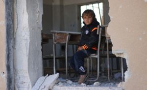 طفل جالس في مدرسة مدمرة - 2016 (يونسيف)
