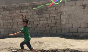 طفل يلعب بطائرة ورقية في مدينة الرقة السورية - 19 تموز 2019 (المصور عبود حمام)

