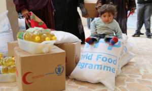 فتاة صغيرة تجلس على المساعدات الغذائية المقدمة من برنامج الغذاء العالمي في دمشق - 2014 (WFP)