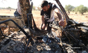 شخص ينظر إلى باص محترق جراء استهدافه خلال عملية الإنزال الأمريكي في باريشا بمحافظة إدلب- 27 من تشرين الأول 2019 (عنب بلدي)