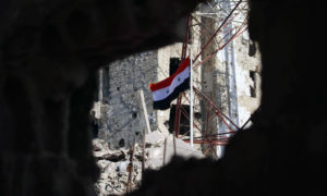راية النظام السوري مرفوعة بين أبنية مهدمة في حي درعا البلد - 12 تموز 2018 (AFP)

