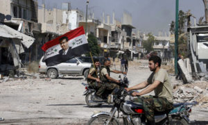 مقاتلون في قوات النظام السوري يحملون راية رسسم عليها صورة بشار الأسد في مدينة القصير بريف حمص بعد السيطرة عليها - 7 حزيران 2013 (رويترز)

