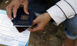 امرأة سورية تُظهر أوراقها للحصول على وضع اللاجئ لدى الأمم المتحدة في لبنان (رويترز)
