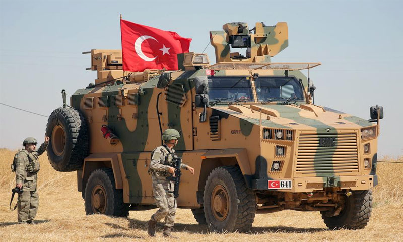 جندي تركي يسير بجوار مركبة عسكرية تركية أثناء دورية مشتركة بين الولايات المتحدة وتركيا بالقرب من تل أبيض ، سوريا 8 أيلول 2019، (رويترز)