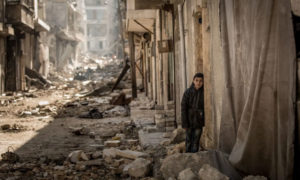 طفل سوري يقف أما بيته المدمر في أحد أحياء مدينة حمص - 13 كانون الأول 2018 (ناشيونال جيوغرافيك)