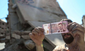 مواطن سوري يحمل فئة نقدية من 2000 ليرة سورية (shutterstock)
