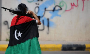 مقاتل ليبي يحمل بندقية، متلحفًا بالعلم الليبي - 17 شباط 2019 (شبكة أرم)