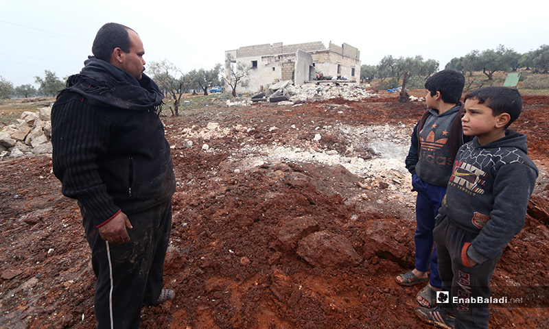 عائلة تجلس أمام منزلها بعد تعرضه للقصف في بلدة كفر تعال بريف حلب الغربي - 20 من كانون الثاني 2020 (عنب بلدي)