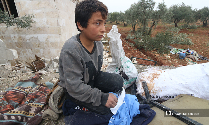 طفل يجمع ما تبقى من أثاث منزله بعد قصفه في بلدة كفر تعال بريف حلب الغربي - 20 من كانون الثاني 2020 (عنب بلدي)