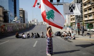 سيدة لبنانية ترفع علم البلاد عند حاجز بشري لمظاهرات مناهضة للحكومة - 4 تشرين الثاني 2019 (رويترز)