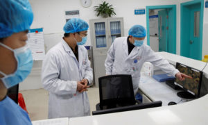 أطباء ينظرون الى شاشة تعرض جناحًا يعالج فيه مصابون بفيروس كورونا الجديد بمستشفى في اقليم هونان بالصين - 27 كانون الثاني 2020 (رويترز)