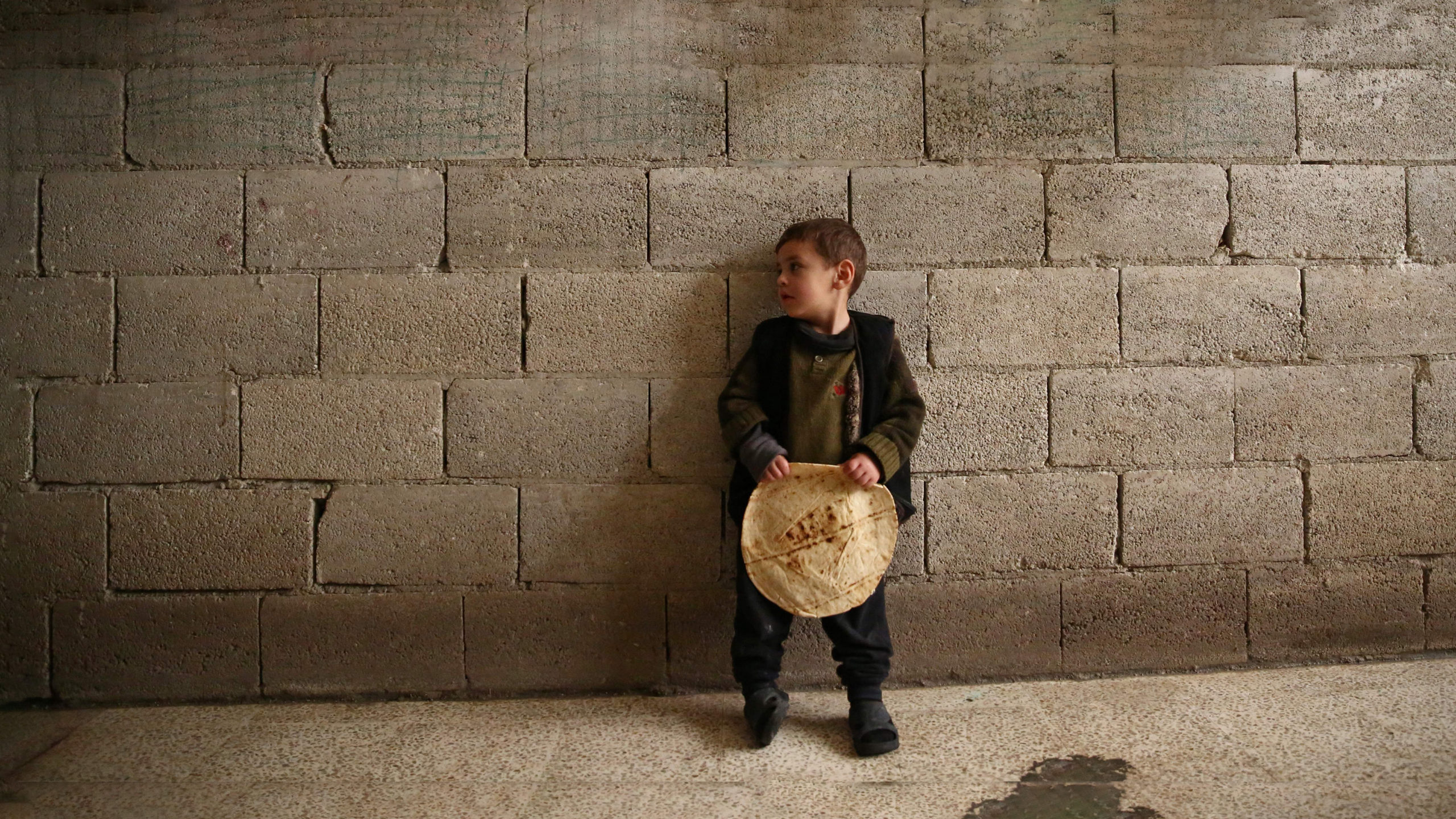 طفل سوري يحمل رغيف خبز (AFP)