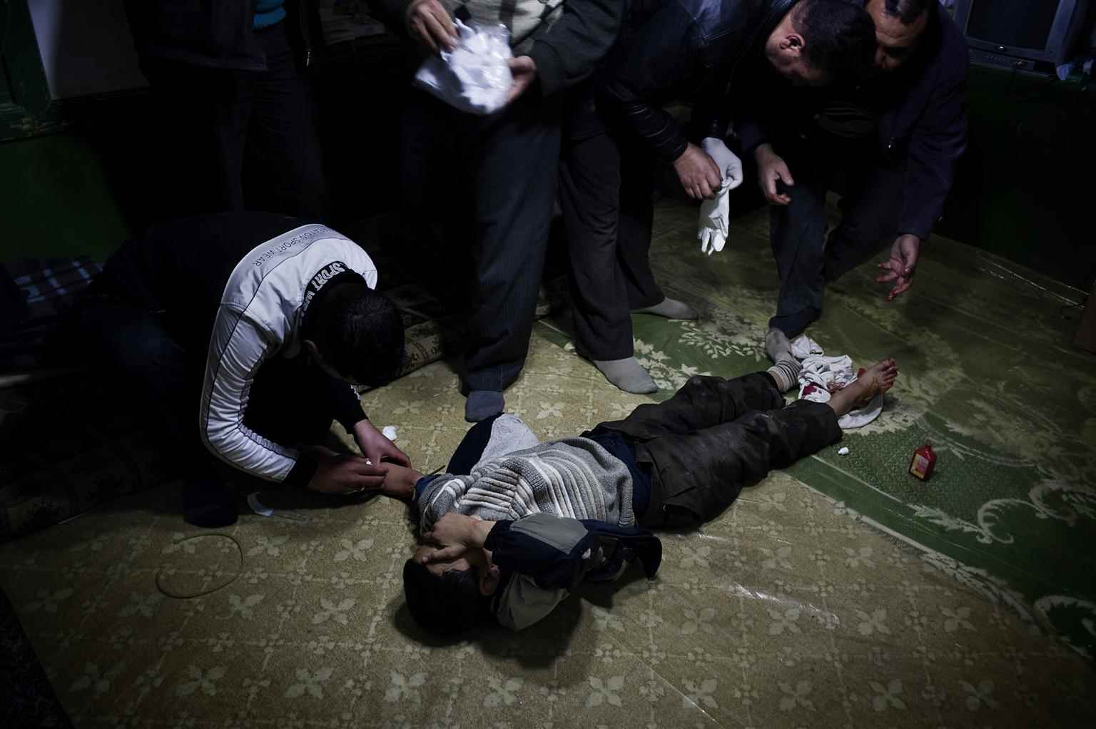 طفل يتلقى الإسعافات الأولية بعد أن أصيب بطلق ناري من قبل قناص في سوريا- كانون الثاني عام  2012 (يونيسيف)