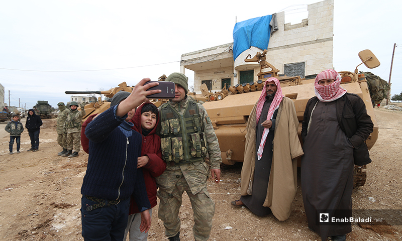 أطفال سوريون يلتقطون صور مع قوات تركية خلال إنشاء نقطة عسكرية جديدة للجيش التركي في بلدة ترمانين شمالي إدلب - 15 شباط 2020 (عنب بلدي)