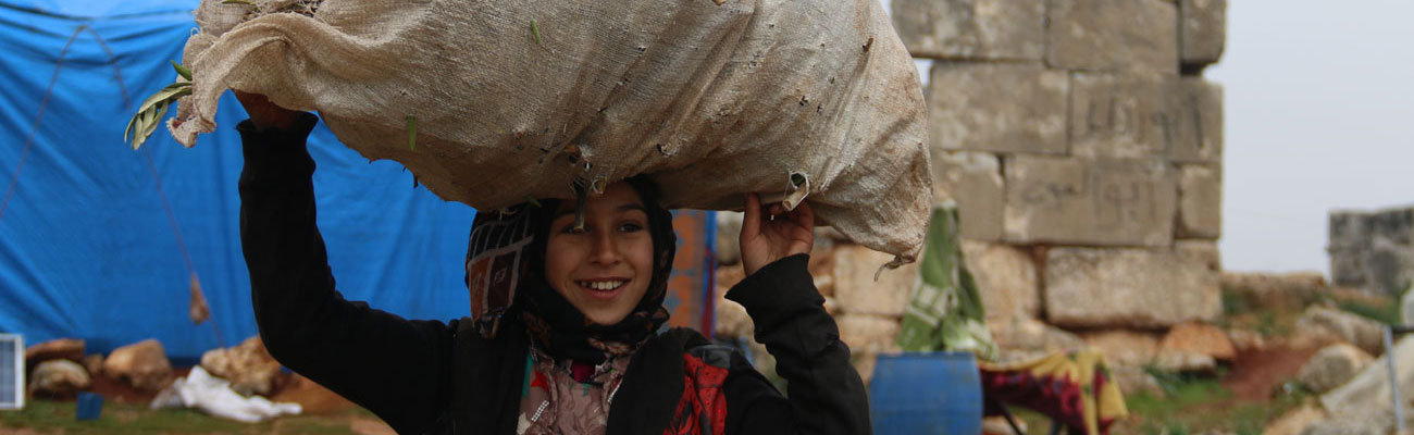 طفلة نازحة تحمل كيسًا من عيدان الخشب في منطقة أثرية بدير نعمان في ريف حلب الغربي - 23 كانون الأول 2020 (عنب بلدي)