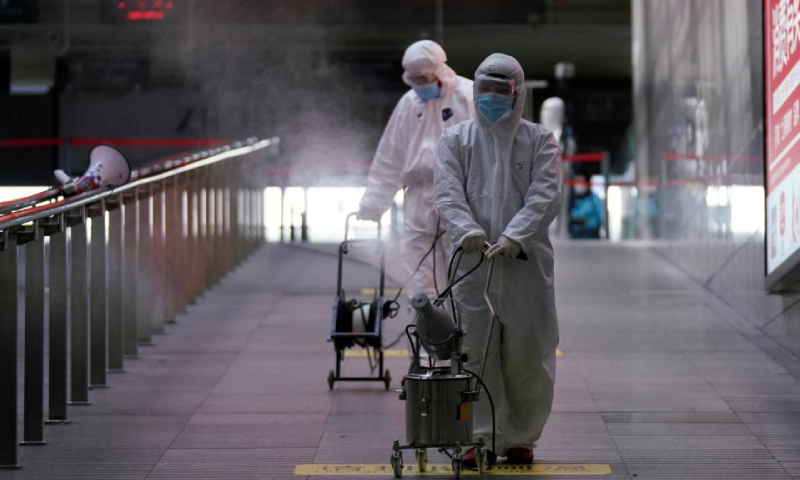 عمال في محطة قطارات بمدينة شنغهاي الصينية يرشون مطهرات لمواجهة انتشار مرض كورونا (رويترز)