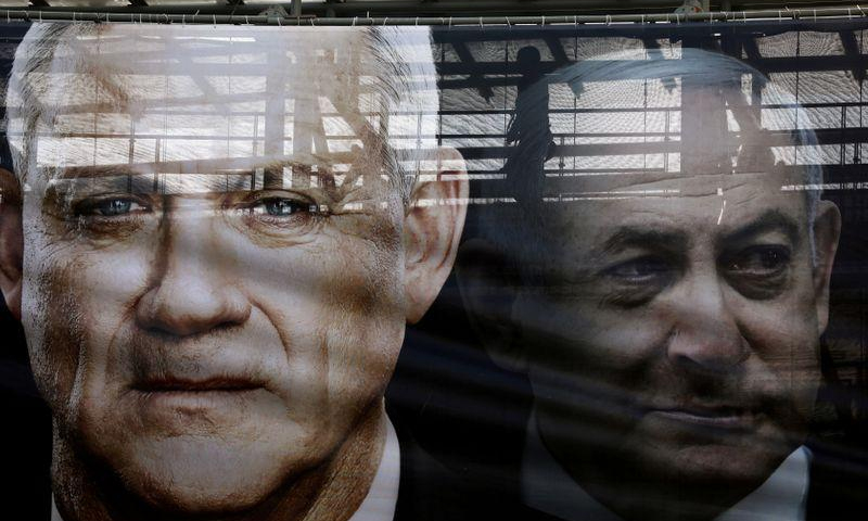 لافتة عليها صورة تجمع رئيس الوزراء الإسرائيلي بنيامين نتنياهو وخصمه الرئيسي بيني جانتس، زعيم حزب أزرق أبيض قبل الانتخابات الأخيرة في شارع بتل أبيب في إسرائيل- 17 شباط 2020 (رويترز).